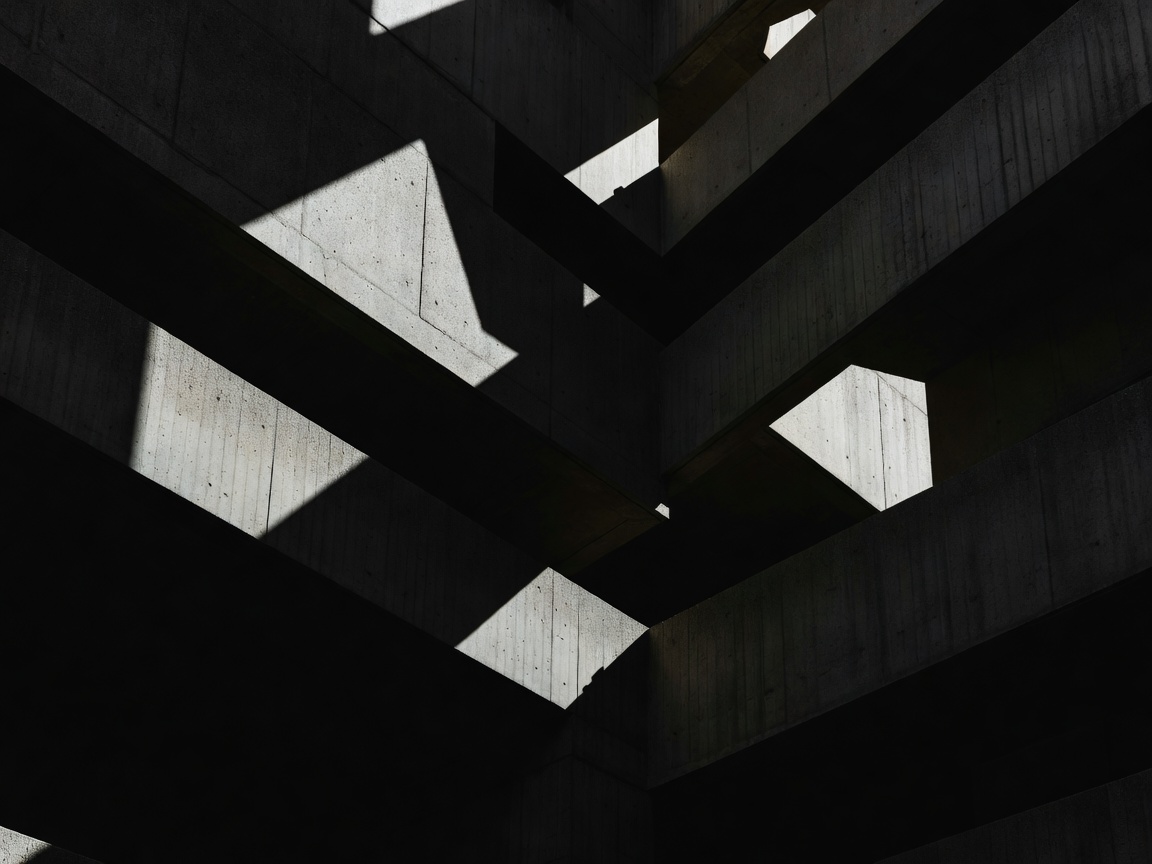 Brutalist architectural concrete patterns of shadow cuts in deep monochrome tone values.